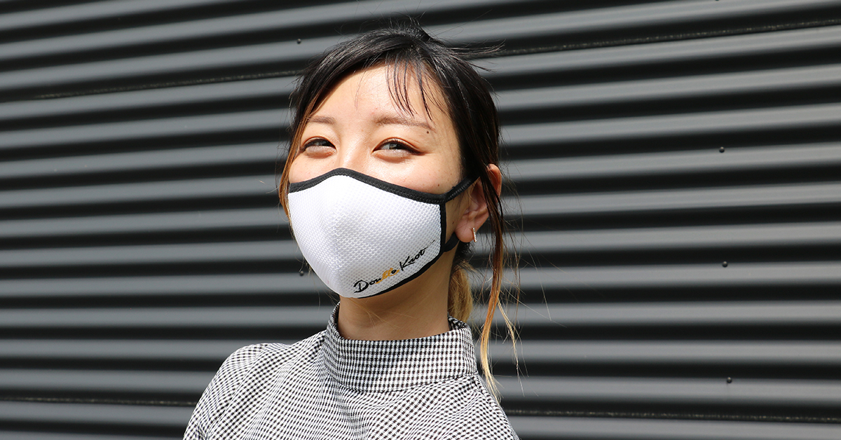 企業ロゴ入りマスクを着用した女性
